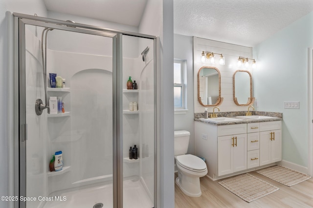 bathroom with hardwood / wood-style floors, a textured ceiling, toilet, and a shower with shower door