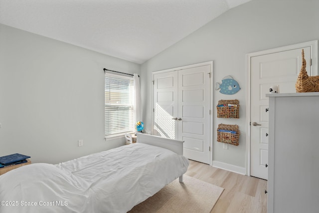 bedroom featuring light wood-type flooring, a closet, and lofted ceiling