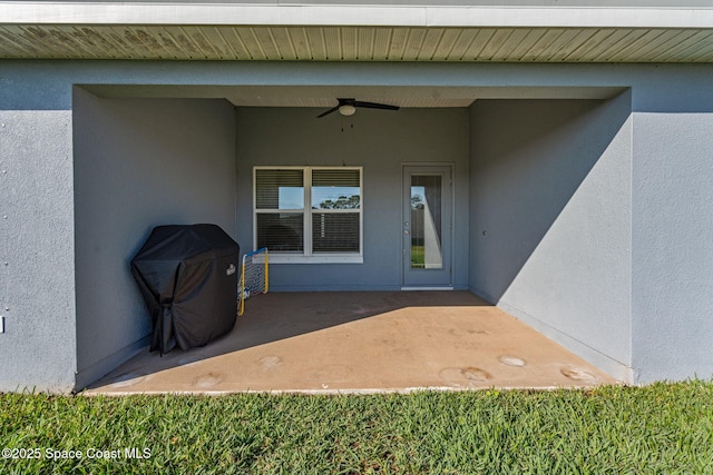 view of exterior entry with ceiling fan and a patio area