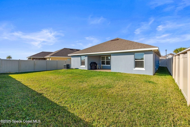 rear view of property with central AC unit and a lawn