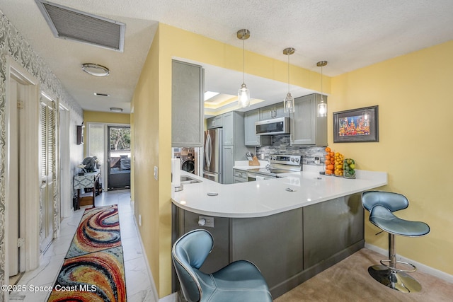 kitchen featuring gray cabinetry, a peninsula, stainless steel appliances, visible vents, and light countertops