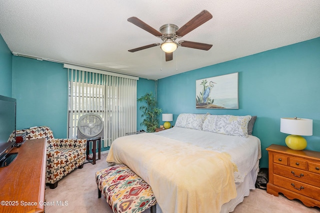 carpeted bedroom featuring ceiling fan and a textured ceiling