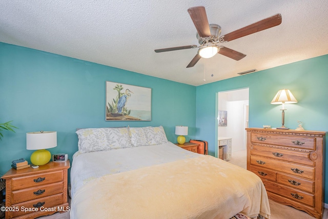 bedroom featuring carpet flooring, connected bathroom, ceiling fan, and a textured ceiling