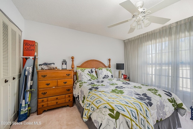 carpeted bedroom featuring ceiling fan, a closet, and a textured ceiling