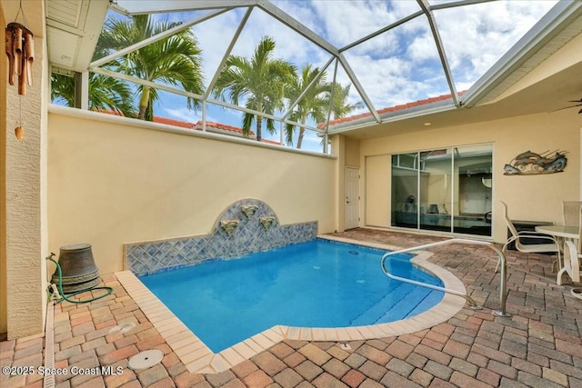 view of pool featuring glass enclosure, pool water feature, and a patio