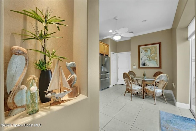 tiled dining area with ceiling fan and crown molding