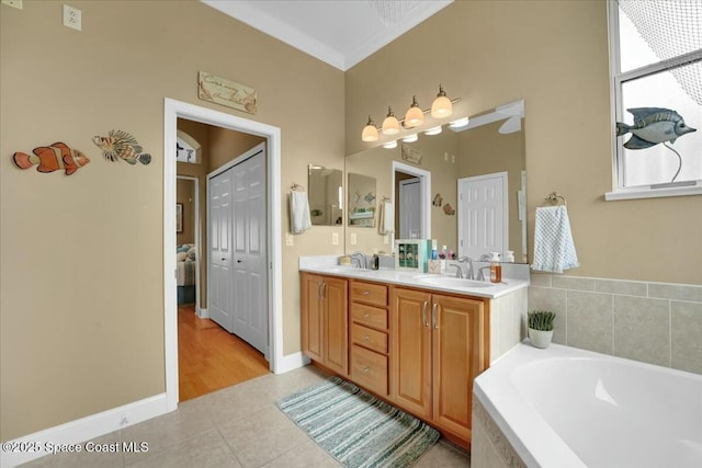 bathroom featuring tile patterned flooring, vanity, tiled bath, and crown molding