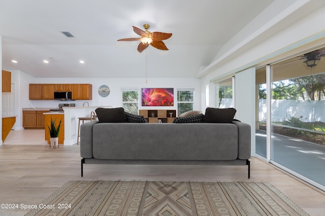 living room with light hardwood / wood-style flooring, a wealth of natural light, lofted ceiling, and ceiling fan