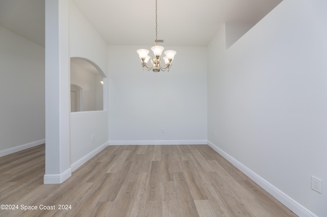 empty room featuring light hardwood / wood-style floors and a notable chandelier