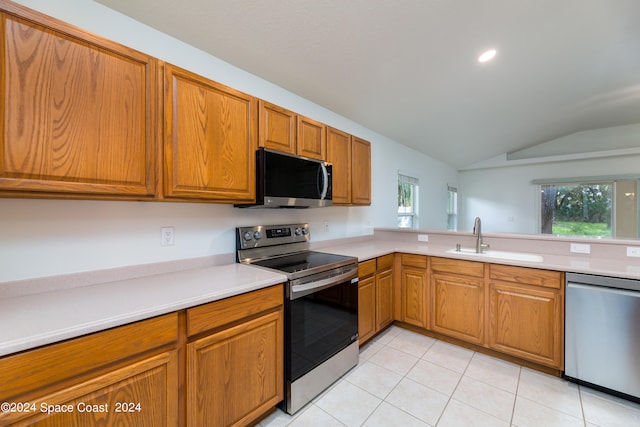 kitchen featuring appliances with stainless steel finishes, a healthy amount of sunlight, lofted ceiling, and sink