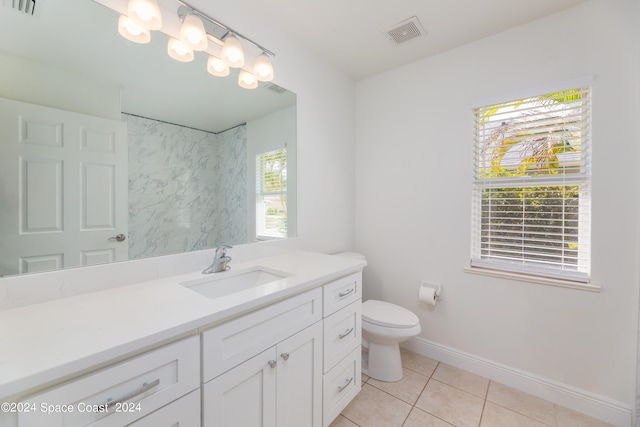 bathroom featuring tile patterned flooring, vanity, toilet, and a healthy amount of sunlight