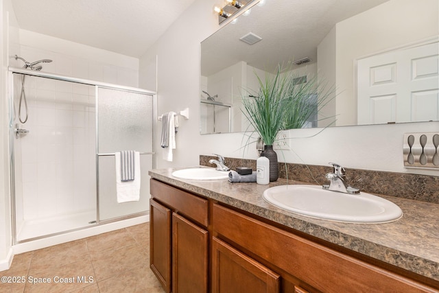 bathroom with walk in shower, vanity, tile patterned flooring, and a textured ceiling