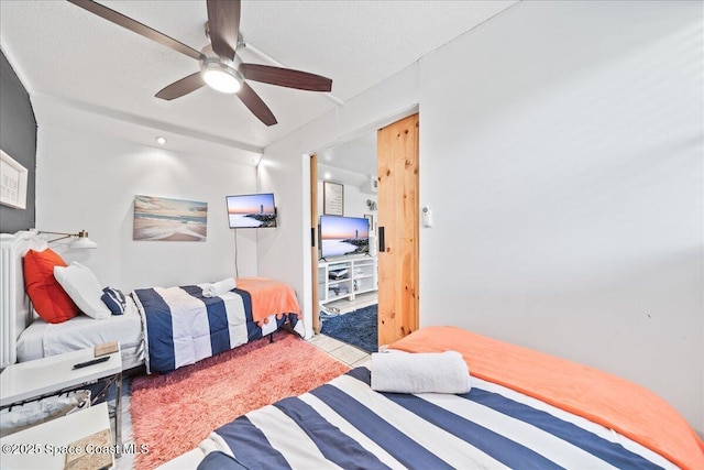 bedroom featuring ceiling fan, light tile patterned floors, and a textured ceiling