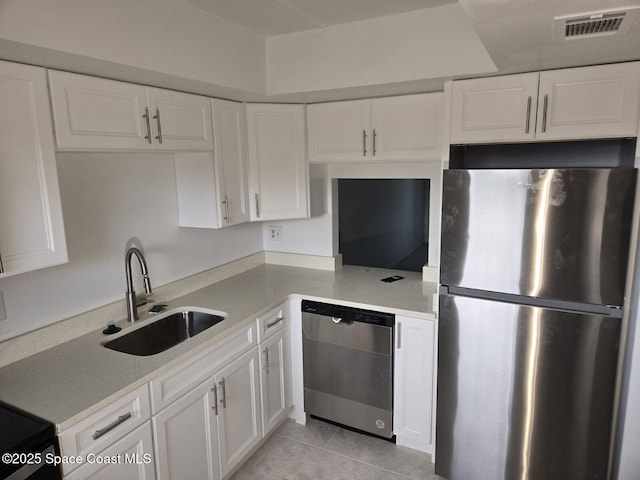 kitchen with sink, white cabinets, light tile patterned flooring, and appliances with stainless steel finishes