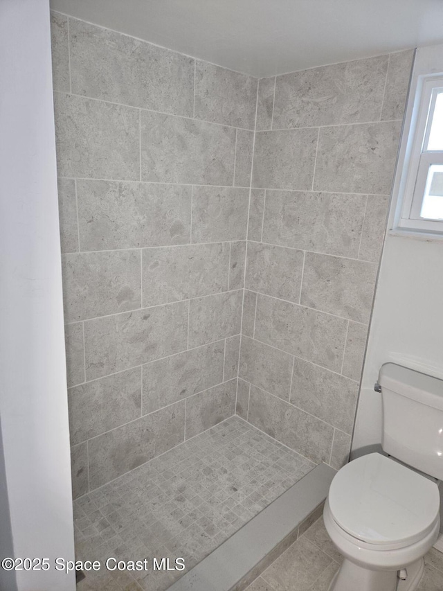 bathroom featuring toilet and a tile shower