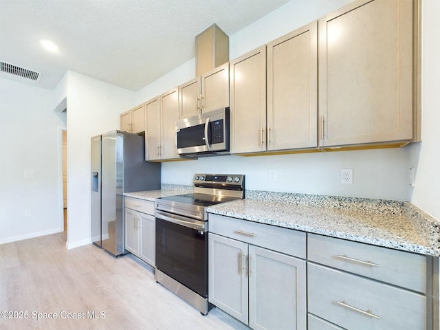 kitchen featuring light stone counters, light wood-type flooring, and appliances with stainless steel finishes