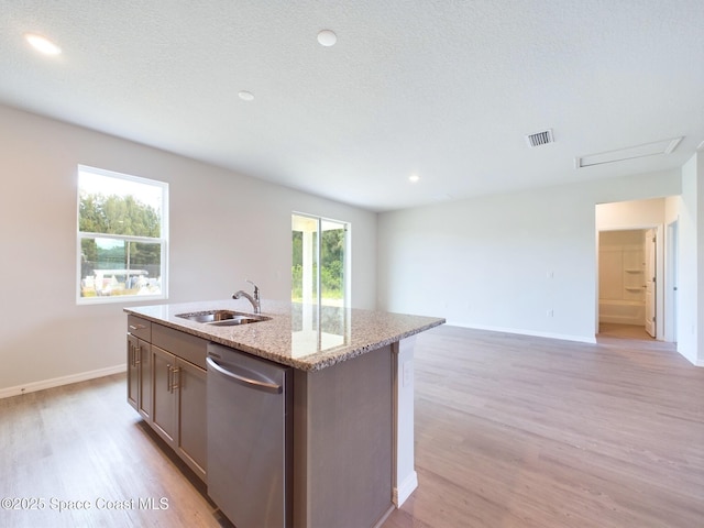 kitchen with sink, light stone counters, light hardwood / wood-style flooring, stainless steel dishwasher, and an island with sink