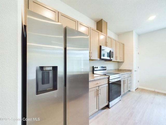 kitchen featuring light stone counters, light brown cabinetry, stainless steel appliances, and light hardwood / wood-style floors