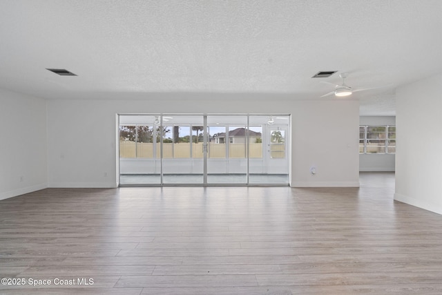 unfurnished room featuring ceiling fan, light hardwood / wood-style floors, and a textured ceiling