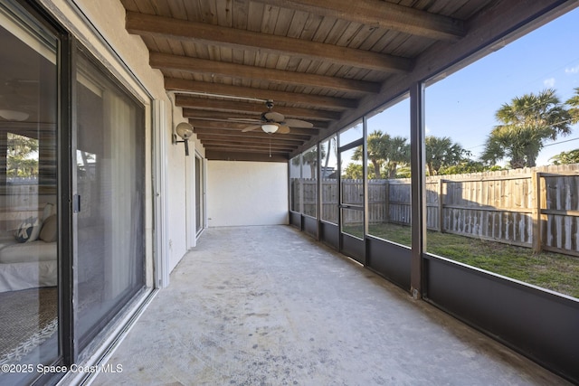 unfurnished sunroom featuring wood ceiling, a healthy amount of sunlight, and beamed ceiling