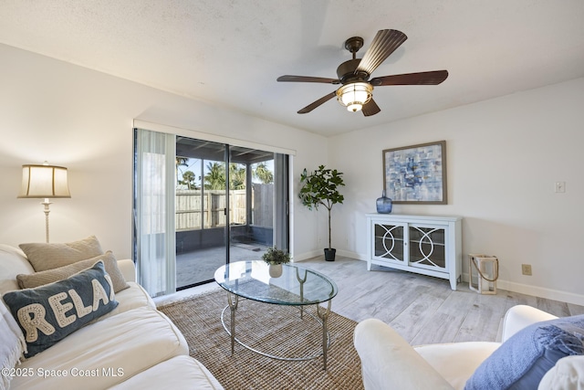 living room with ceiling fan, a textured ceiling, and light hardwood / wood-style flooring