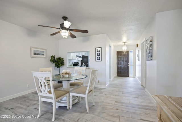 dining space featuring ceiling fan, a textured ceiling, and light hardwood / wood-style flooring