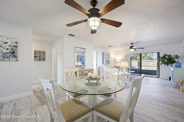 dining area with ceiling fan, light wood-type flooring, and a textured ceiling