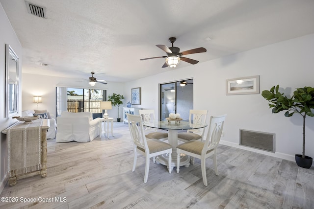 dining area featuring a textured ceiling and light hardwood / wood-style flooring