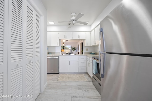 kitchen with white cabinetry, light hardwood / wood-style floors, ceiling fan, appliances with stainless steel finishes, and sink