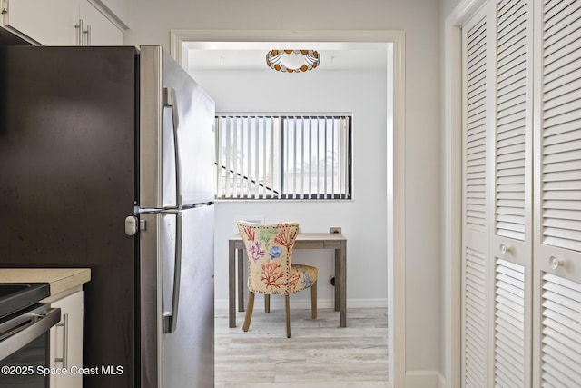 kitchen with white cabinets, stainless steel fridge, and light hardwood / wood-style flooring