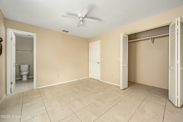 unfurnished bedroom featuring connected bathroom, ceiling fan, a closet, and light tile patterned flooring