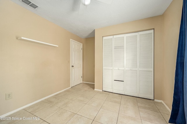 unfurnished bedroom featuring ceiling fan, a closet, and light tile patterned floors