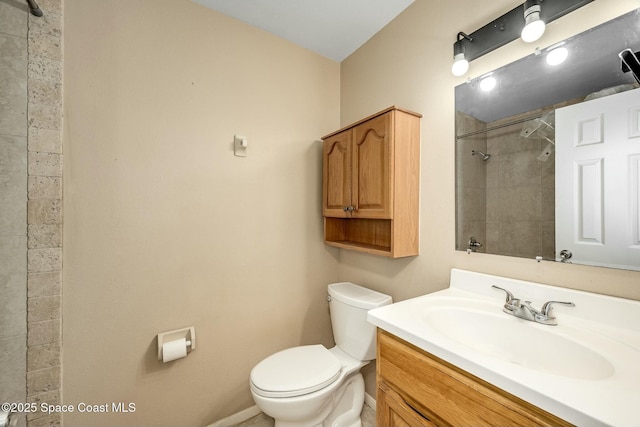 bathroom with a tile shower, vanity, and toilet