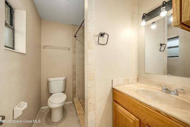 bathroom featuring tile patterned floors, vanity, a tile shower, and toilet