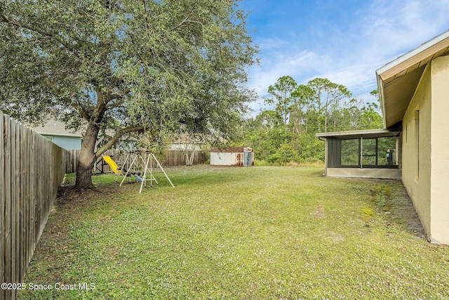 view of yard featuring a playground, a sunroom, and a storage unit