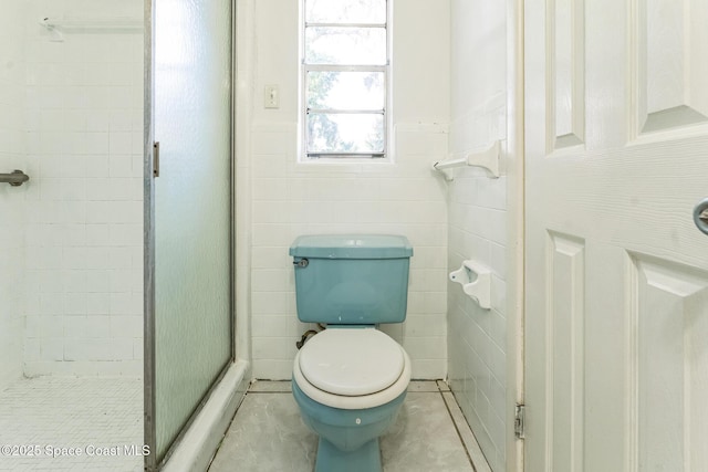 bathroom featuring a shower with shower door and toilet