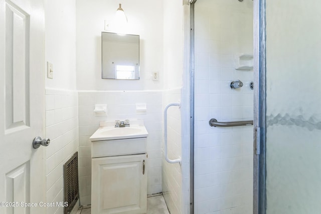 bathroom with vanity, walk in shower, and tile walls