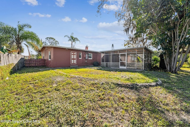 rear view of house with a sunroom and a yard