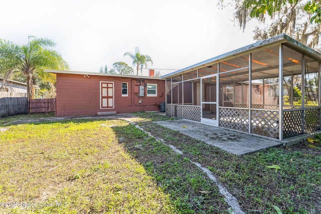 rear view of house featuring a lawn and a sunroom