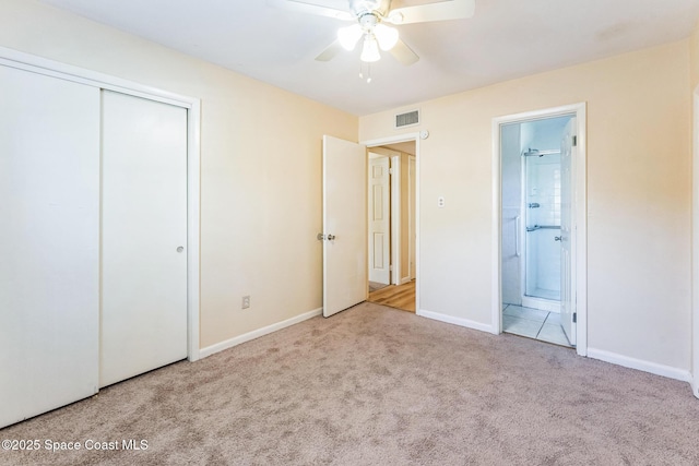 unfurnished bedroom with ensuite bath, ceiling fan, a closet, and light carpet