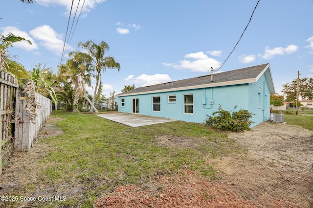 rear view of property with cooling unit, a yard, and a patio