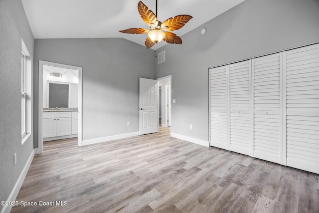 unfurnished bedroom featuring light wood-type flooring, ensuite bathroom, ceiling fan, high vaulted ceiling, and a closet