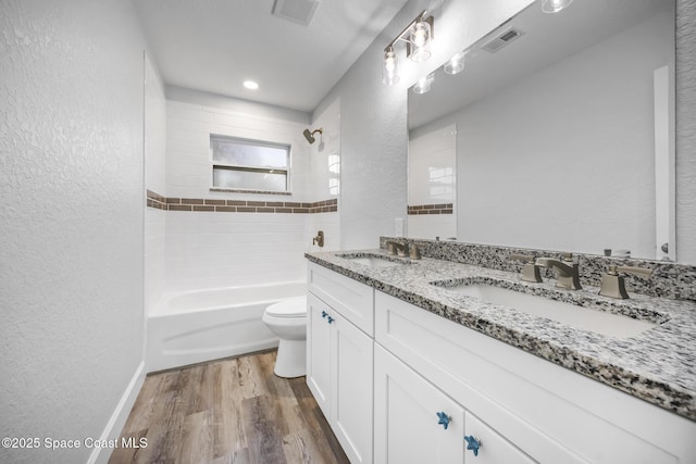 full bathroom featuring hardwood / wood-style floors, vanity, toilet, and tiled shower / bath