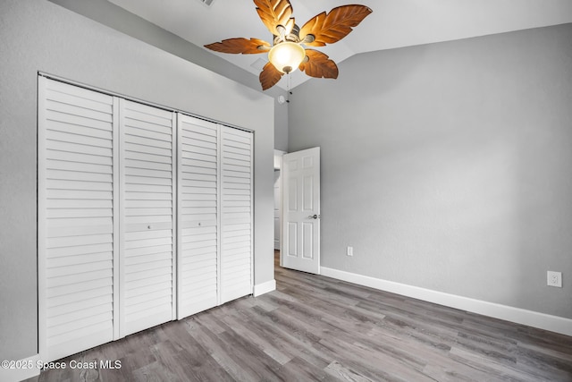 unfurnished bedroom featuring hardwood / wood-style flooring, ceiling fan, lofted ceiling, and a closet