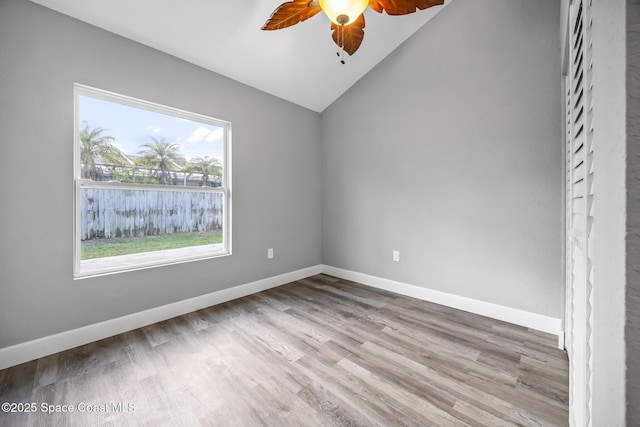 empty room with ceiling fan, a water view, lofted ceiling, and light wood-type flooring