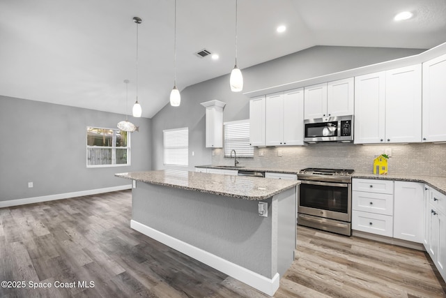 kitchen with a kitchen island, stainless steel appliances, white cabinetry, and lofted ceiling