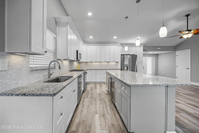 kitchen with white cabinetry, sink, pendant lighting, a kitchen island, and appliances with stainless steel finishes