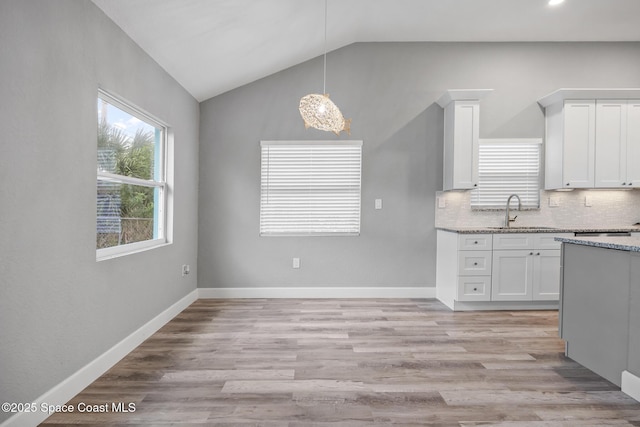 kitchen with white cabinetry, sink, backsplash, pendant lighting, and vaulted ceiling