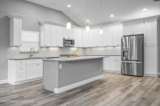 kitchen featuring lofted ceiling, white cabinets, decorative light fixtures, and appliances with stainless steel finishes