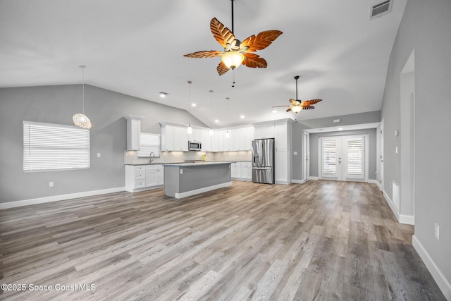 kitchen with hanging light fixtures, stainless steel appliances, a kitchen island, backsplash, and white cabinets